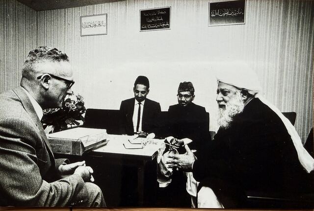 Hazrat Khalifatul Masih III in conversation with a European man at a table.