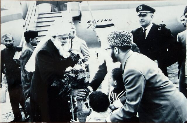 Children handing flowers to Hazrat Khalifatul Masih III beside the aircraft.