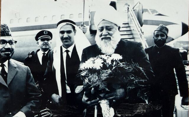 Hazrat Khalifatul Masih III walking with a group of men at the airport.