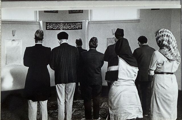 Worshippers standing in prayer, seen from behind.