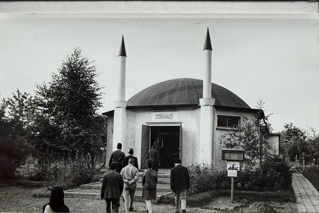 The domed mosque with two minarets, people walking to the door.